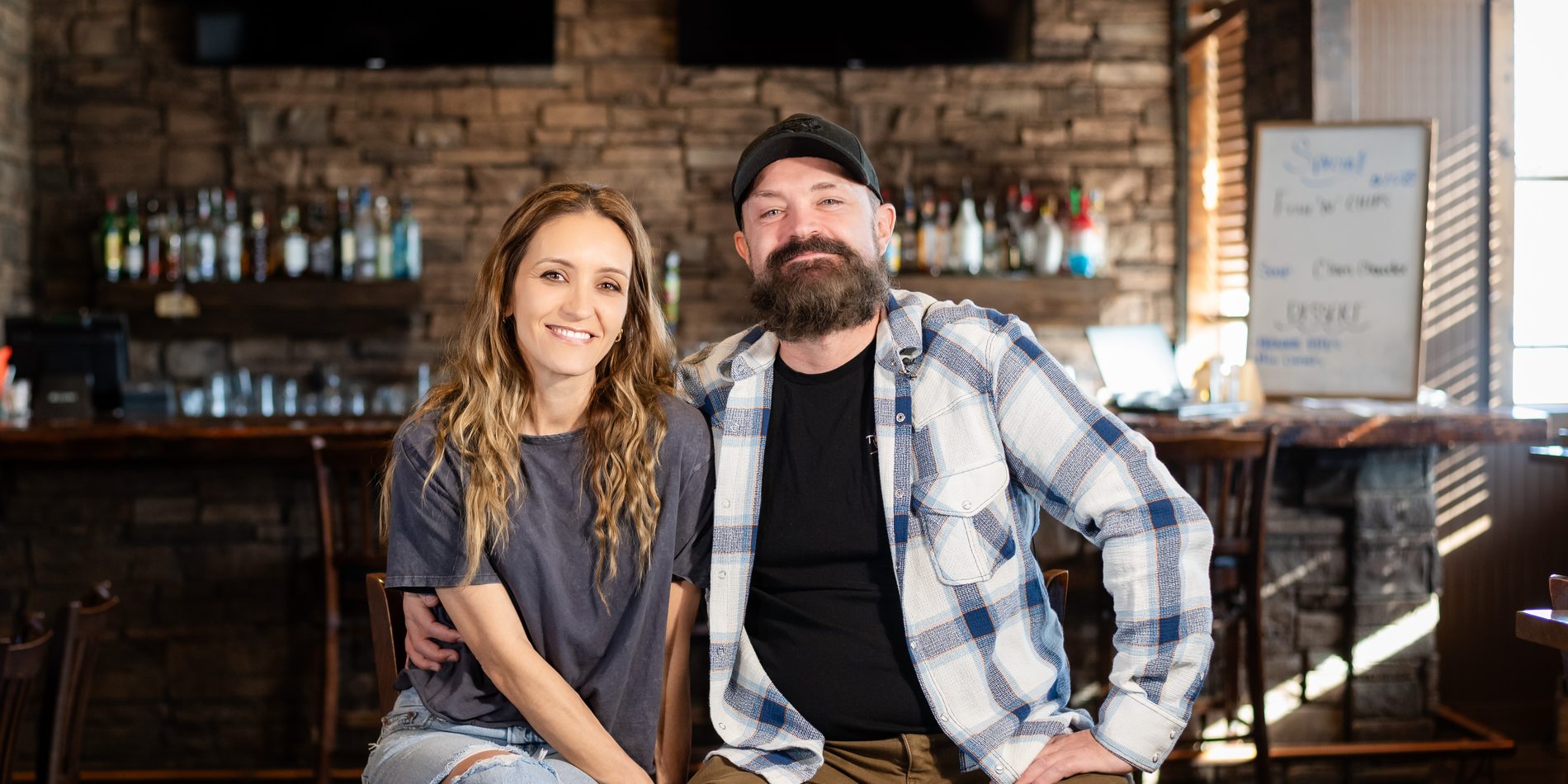 Two owners sitting together at the bar of their restaurant