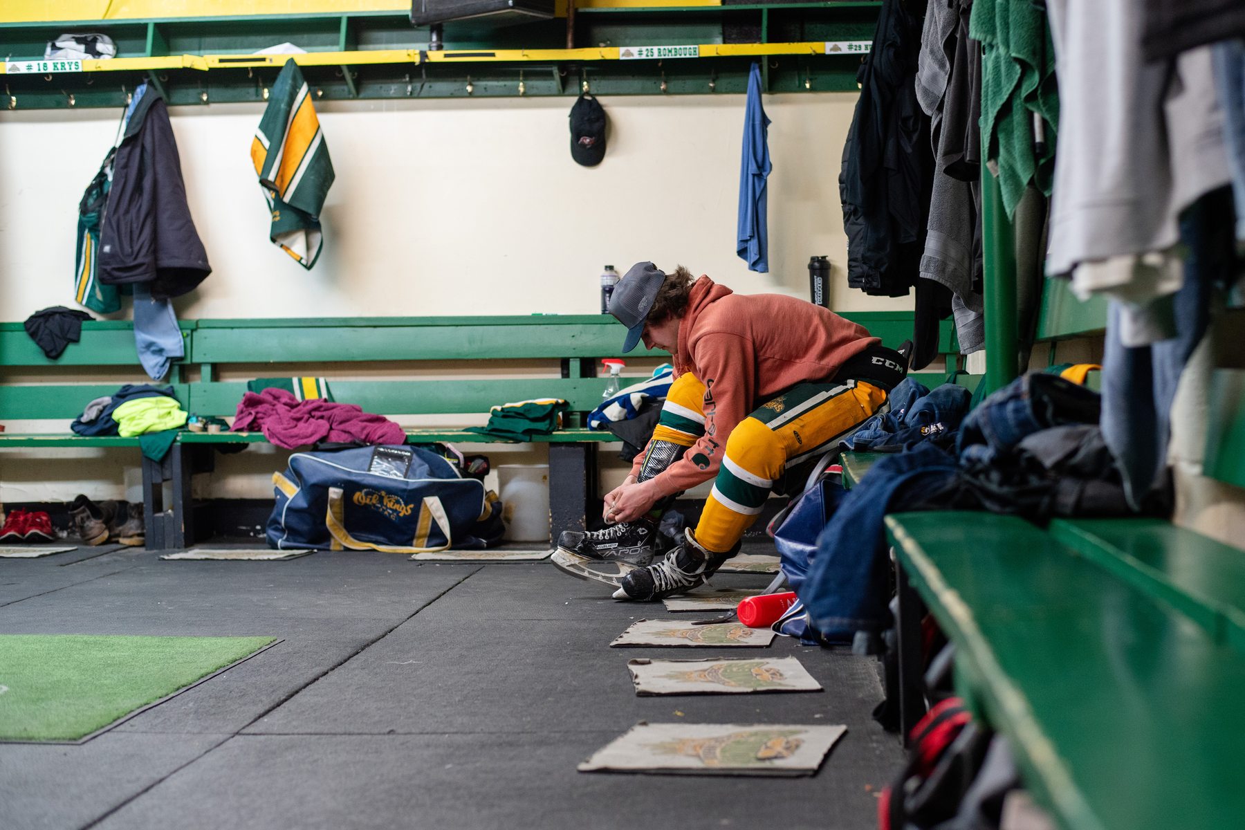 A player lacing his skates alone in a small town hockey dressing room
