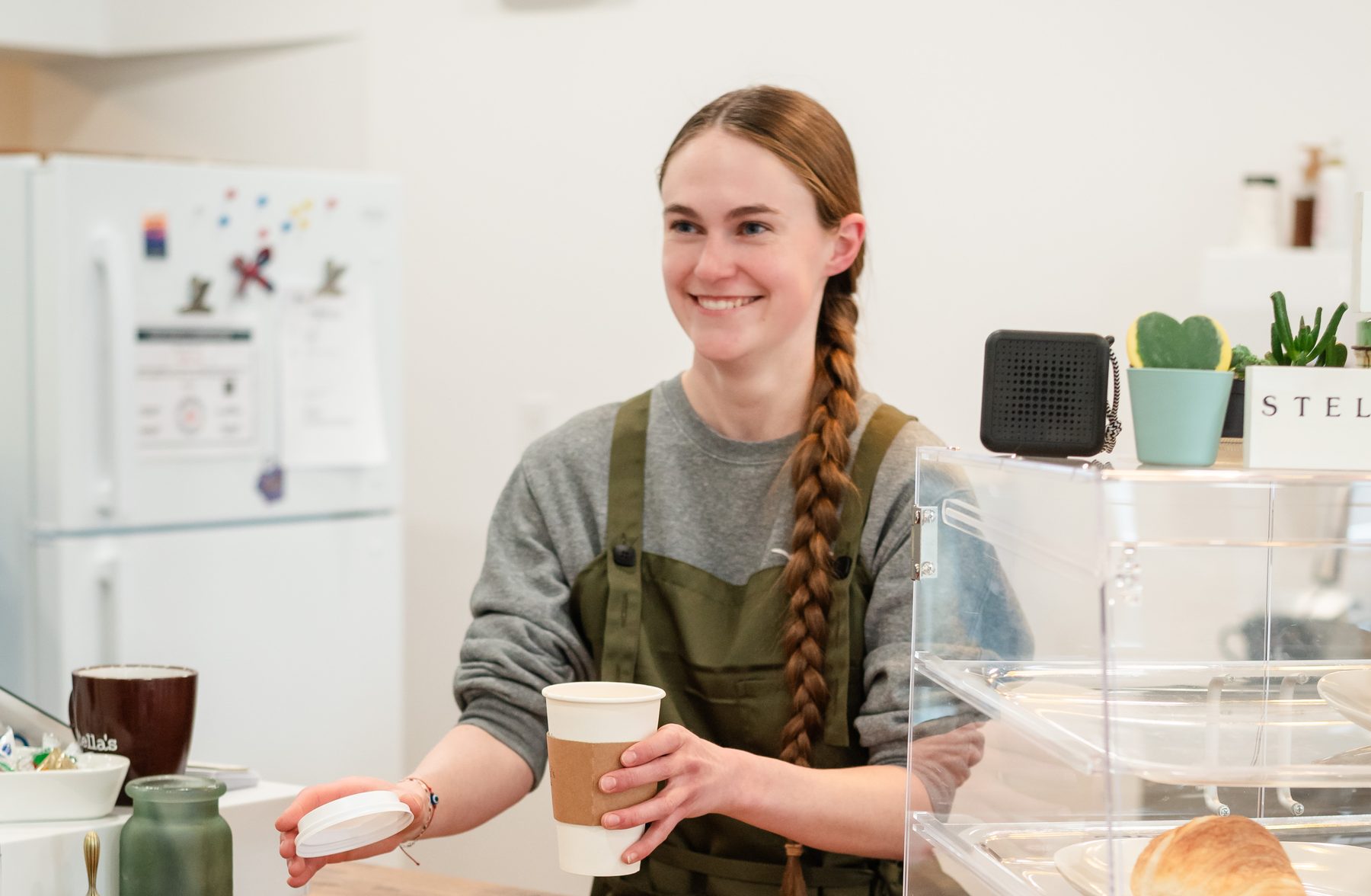 A barista handing a coffee across the counter of a small town cafe
