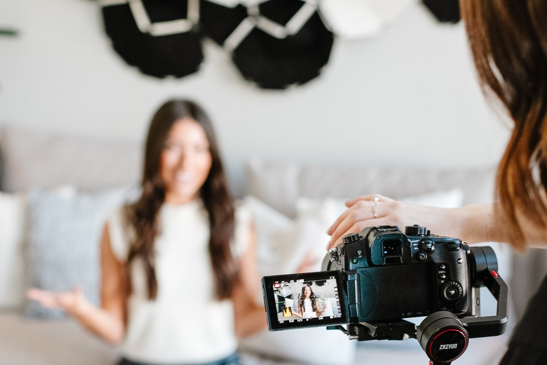 Josie Storbakken holding a camera on a gimbal, filming an interview in a living room